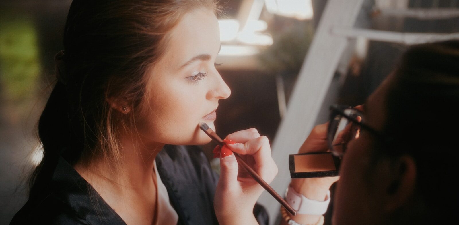 a woman is putting lipstick on her lips